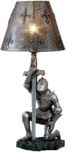 Kneeling knight sword table lamp lit, with dotted light through the fleur-de-lis shade