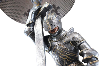 Close up of the knight in full plate armor with head bowed over the sword