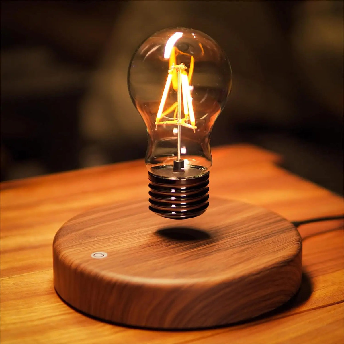Levitating Edison bulb lamp glowing warm amber as it floats above a round wood grain base