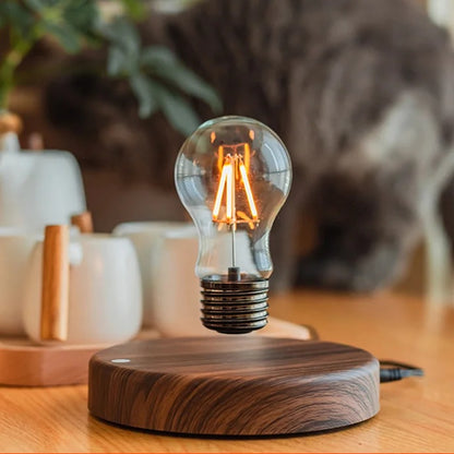 Levitating bulb lamp glowing on a cozy table next to cups and a plant